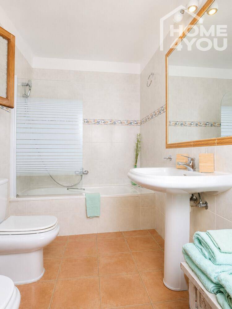 Helles Badezimmer mit Badewanne, Standwaschbecken und traditionellen Fliesen.