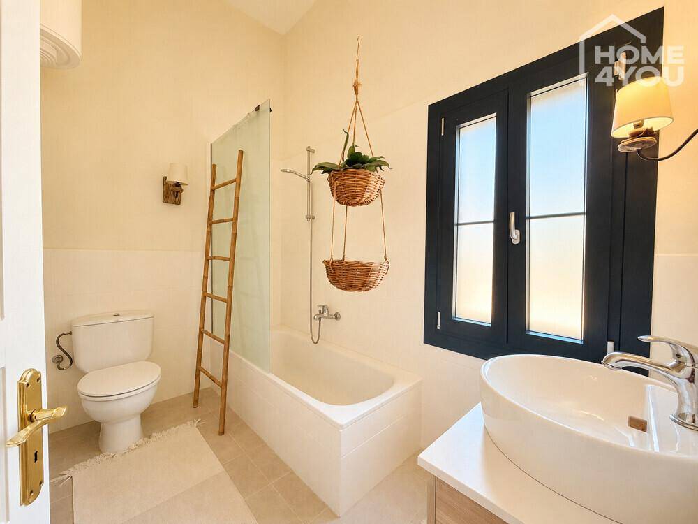 Helles Badezimmer mit Badewanne, WC, Waschbecken und Fenster.
