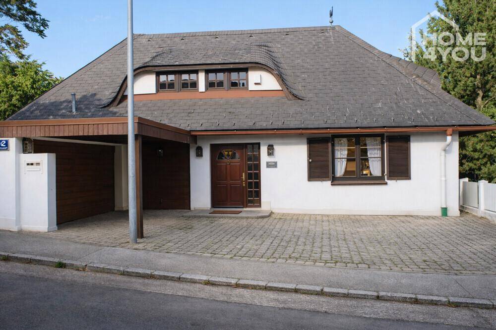 Ansicht des Hauses von der Straße mit gepflasterter Einfahrt und Carport.