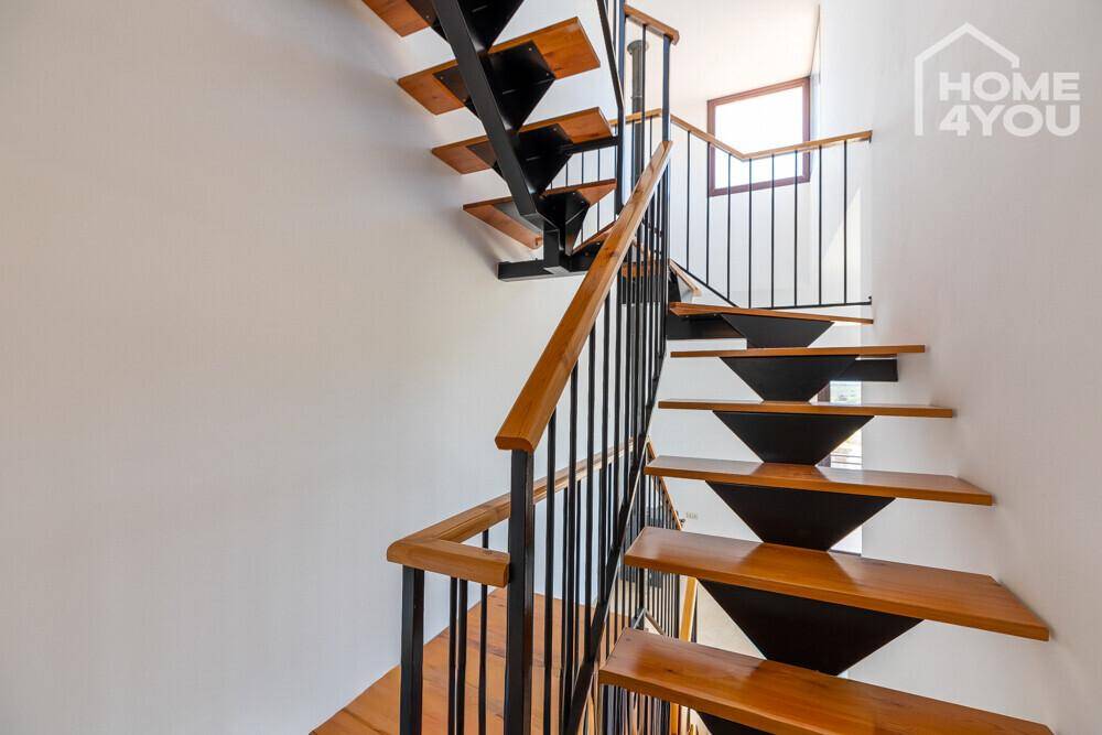 Moderne Holztreppe mit schwarzem Metallgeländer, die verschiedene Ebenen des Hauses verbindet.