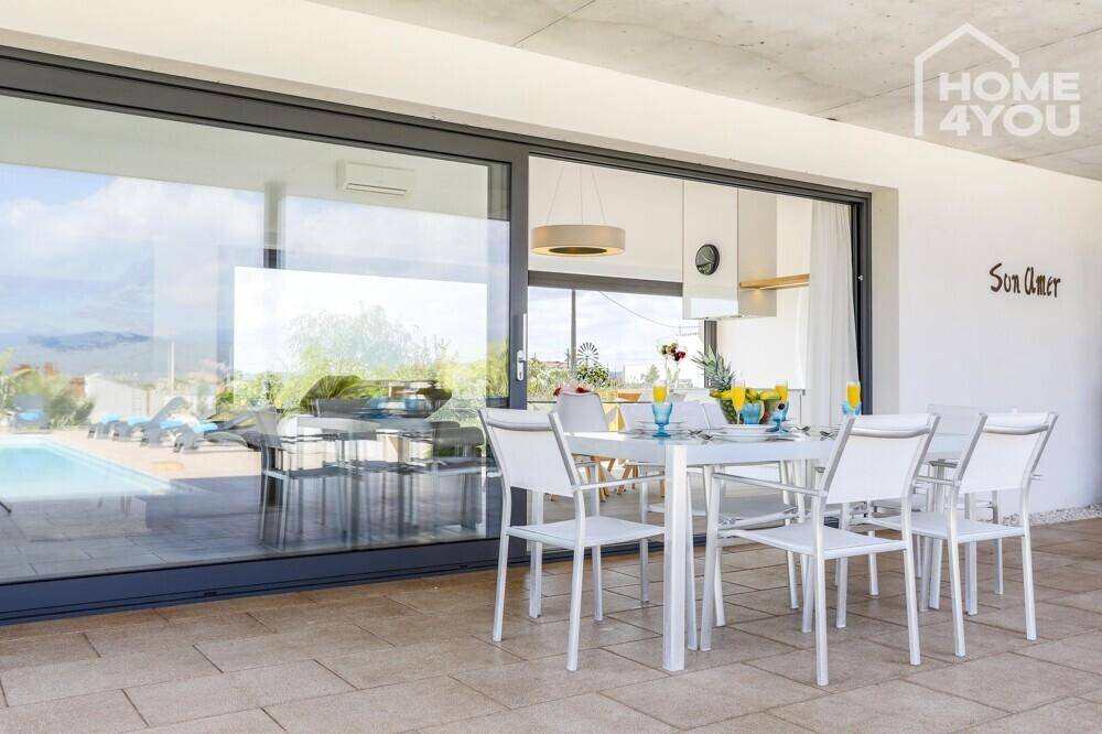 Überdachte Terrasse mit Esstisch und Blick auf den Poolbereich und die umliegende Landschaft.
