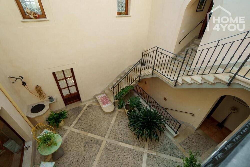 Blick von oben auf den Innenhof mit Treppe, Pflanzen und traditionellen Elementen.