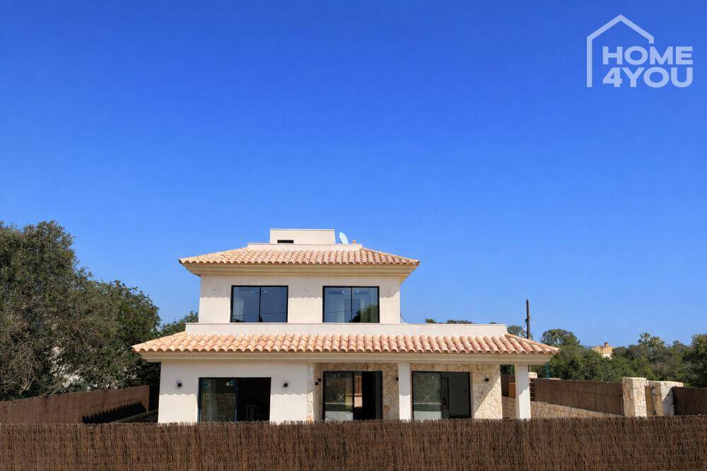 Ansicht der modernen Villa mit traditionellem Ziegeldach und umzäuntem Grundstück.