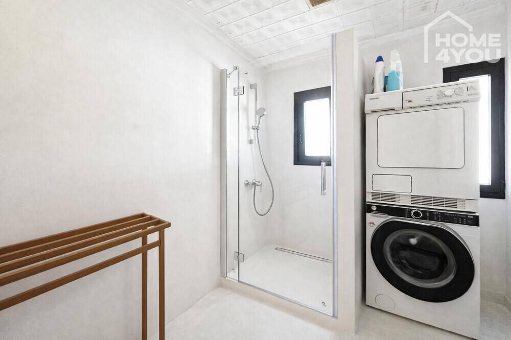 Praktischer Waschraum mit Dusche, Waschmaschine und Trockner übereinander gestapelt.