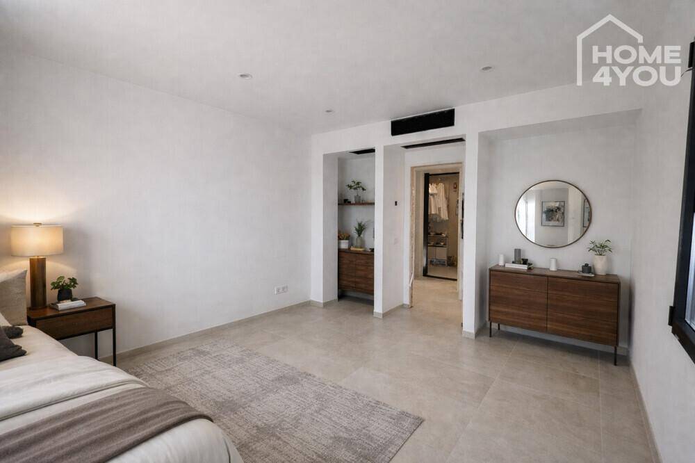 Geräumiges Schlafzimmer mit modernem Interieur und Zugang zu einem Ankleidebereich.