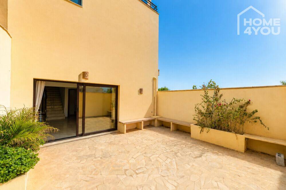 Geräumige Terrasse mit Steinboden, integrierten Sitzgelegenheiten und Zugang zum Innenbereich des Hauses.