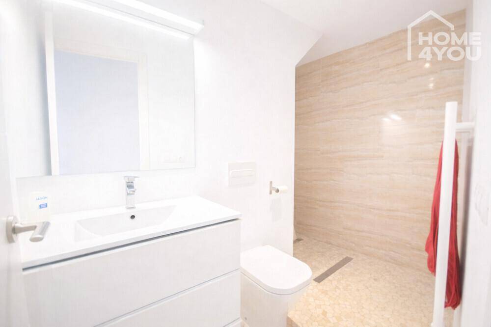 Modernes Badezimmer mit begehbarer Dusche, eleganten Fliesen und beheiztem Handtuchhalter.