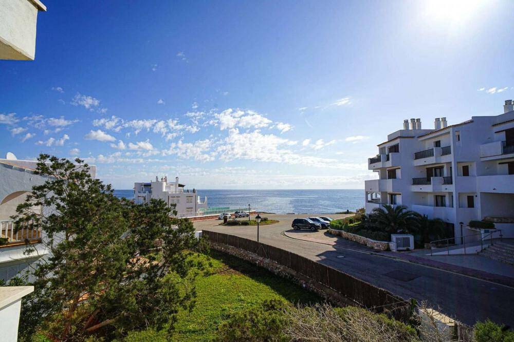 Panoramablick auf die Küste mit Gebäuden, Straße und Meer unter strahlend blauem Himmel.