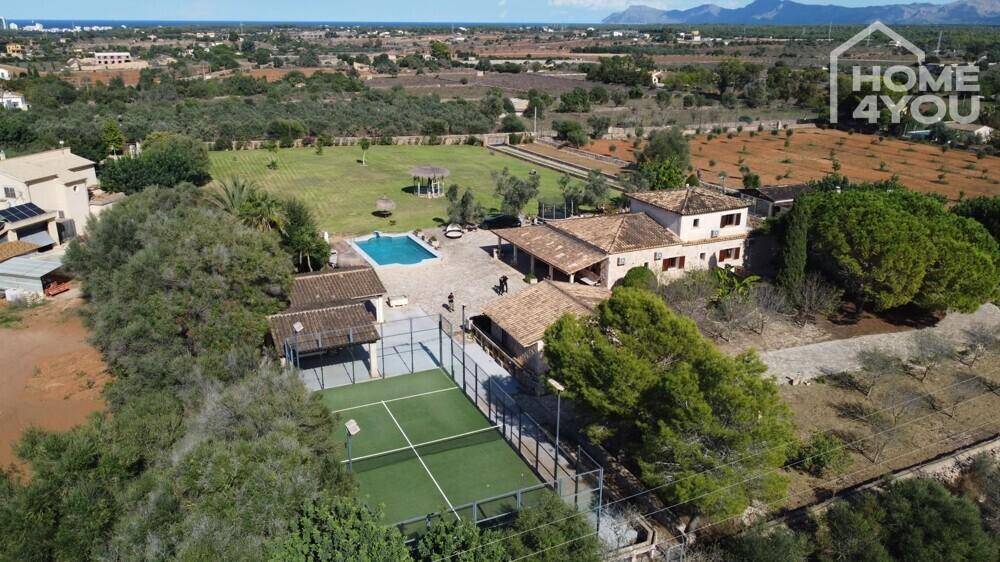 Weitläufiges Anwesen mit Tennisplatz, Poolbereich und Blick auf die umliegende Landschaft und das Meer.