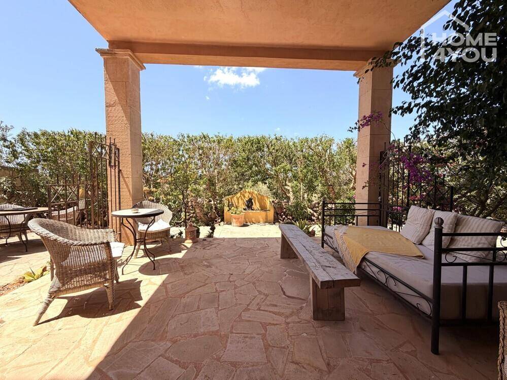 Überdachte Terrasse mit Sitzgelegenheiten und Blick auf die grüne Umgebung.