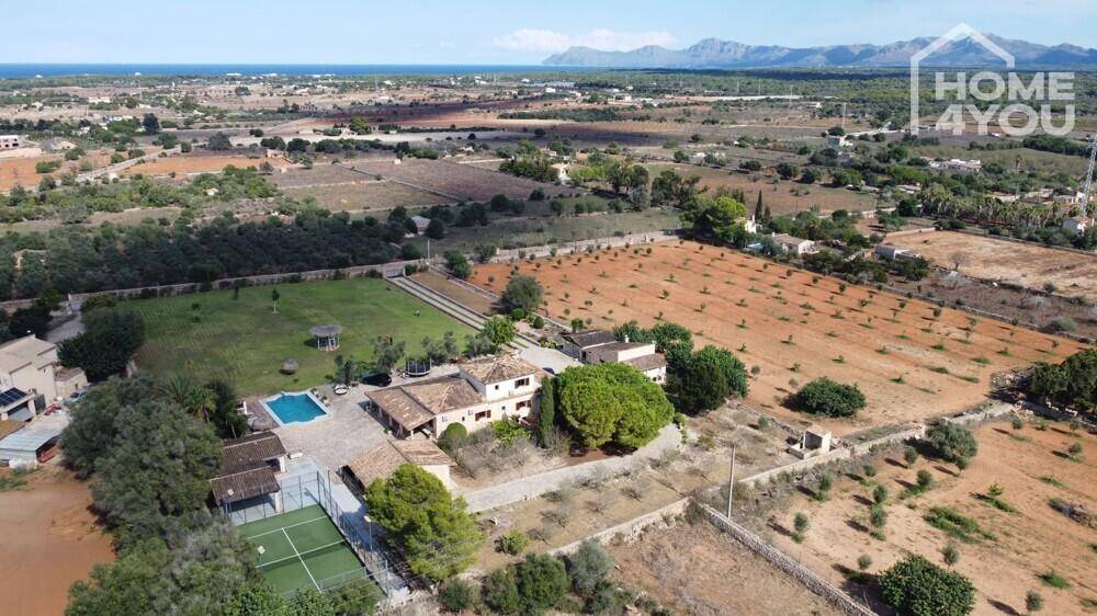 Panoramablick auf das Landgut mit großem Poolbereich, Tennisplatz und weiten Feldern.