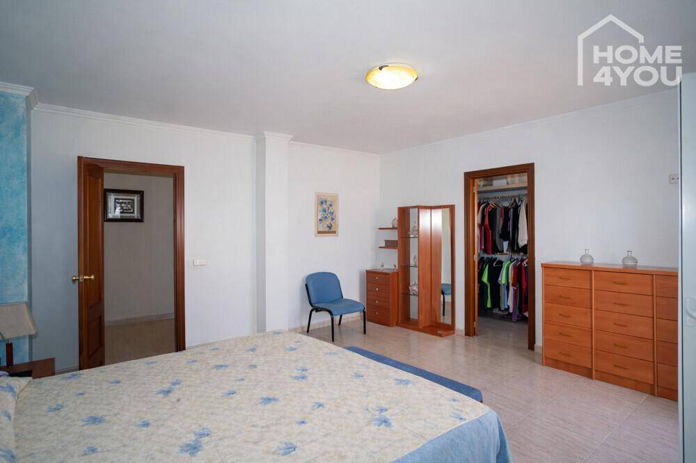Großes Schlafzimmer mit Holzkommoden und direktem Zugang zu einem begehbaren Kleiderschrank.