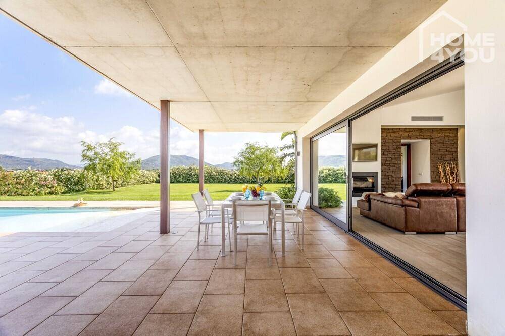 Geräumige überdachte Terrasse mit Essbereich und weitem Blick auf den Garten und die Berge.