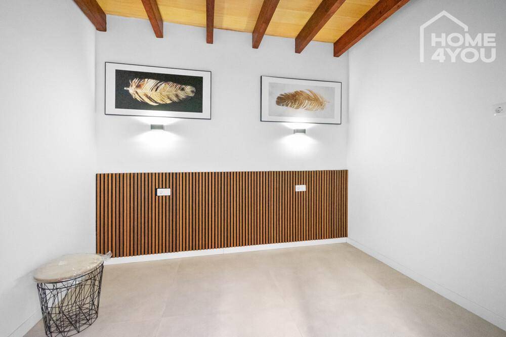 Leeres Schlafzimmer mit dekorativer Holzwandverkleidung und sichtbaren Holzbalken an der Decke.