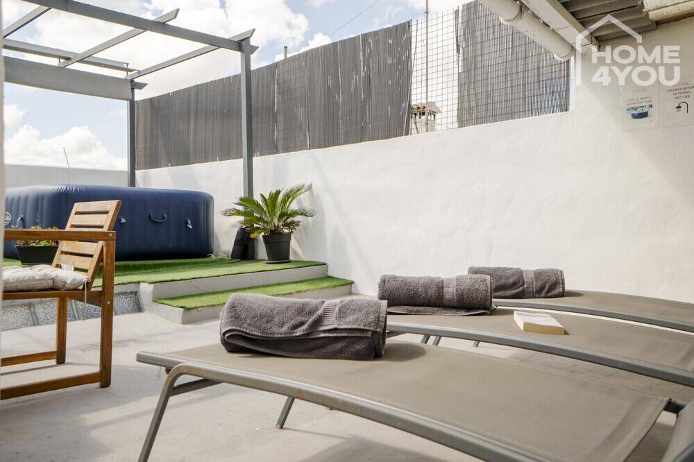 Entspannende Dachterrasse mit Sonnenliegen, aufblasbarem Whirlpool und Pergola-Struktur.
