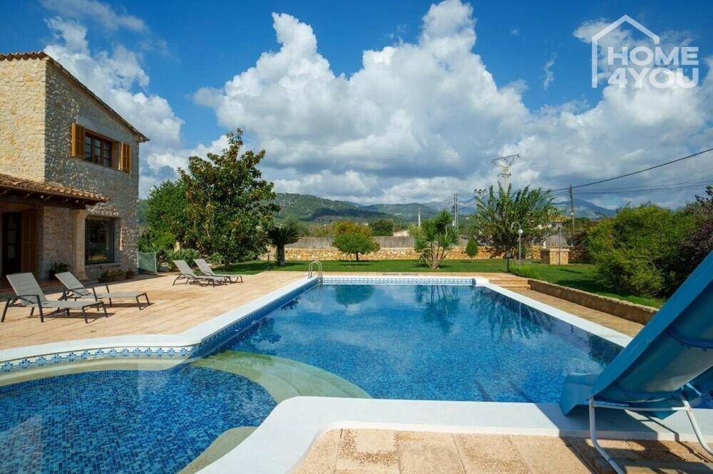 Großer Swimmingpool mit Rutsche, Liegeflächen und weitem Blick auf die Berge.