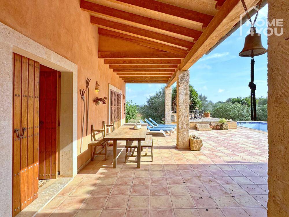 Überdachte Terrasse mit Holzbalken und Esstisch, ideal für Mahlzeiten im Freien am Pool.