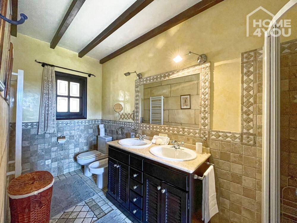 Geräumiges Badezimmer mit Doppelwaschbecken, Fliesenwänden, Bidet und Duschkabine.