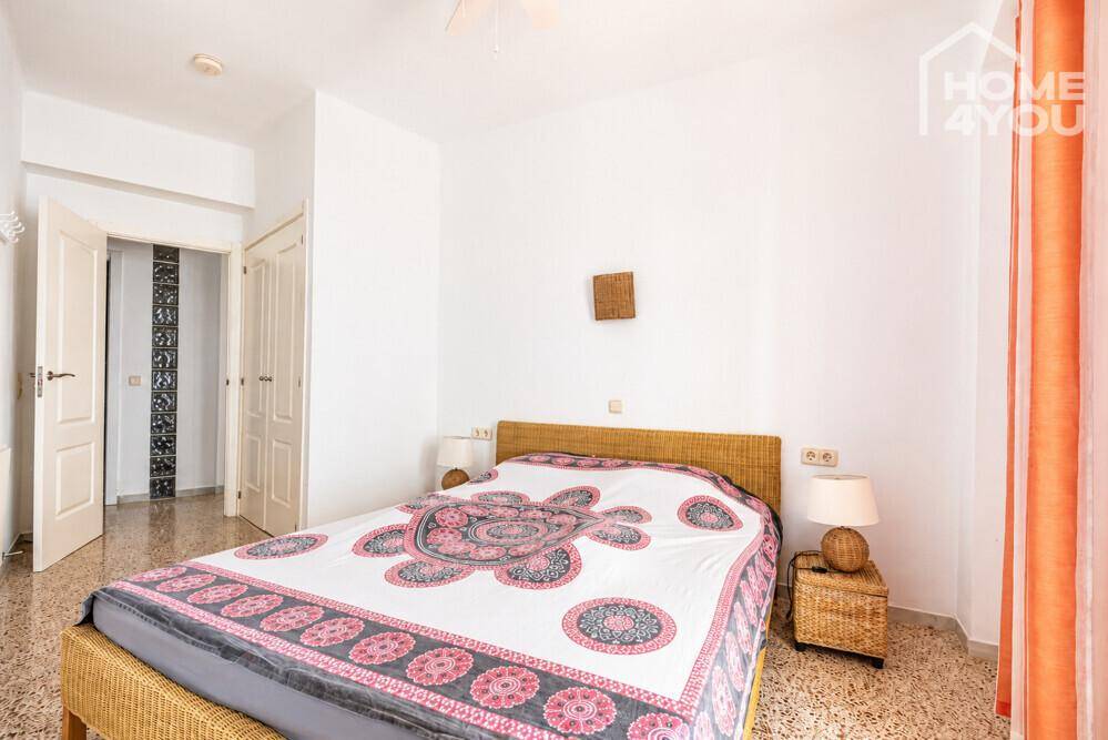Gemütliches Schlafzimmer mit Rattanbett, Deckenventilator und Zugang zu einem Flur.