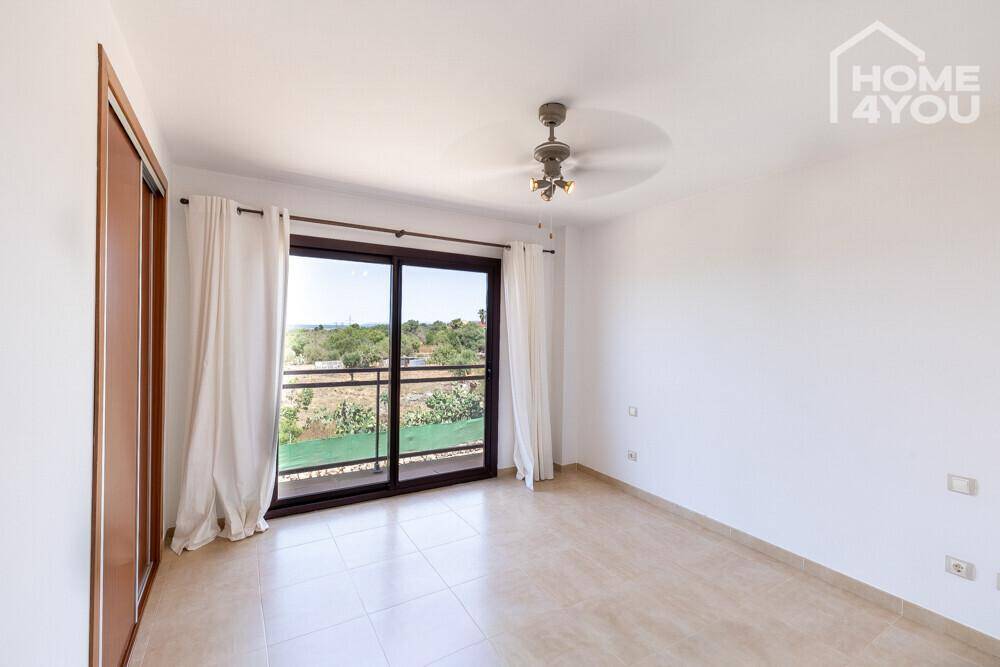 Geräumiges Schlafzimmer mit Fliesenboden, Einbauschrank und großen Fenstern mit weitem Ausblick.