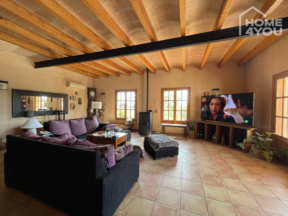Gemütliches Wohnzimmer mit Holzbalkendecke, Kaminofen und Fliesenboden, ideal zum Entspannen.