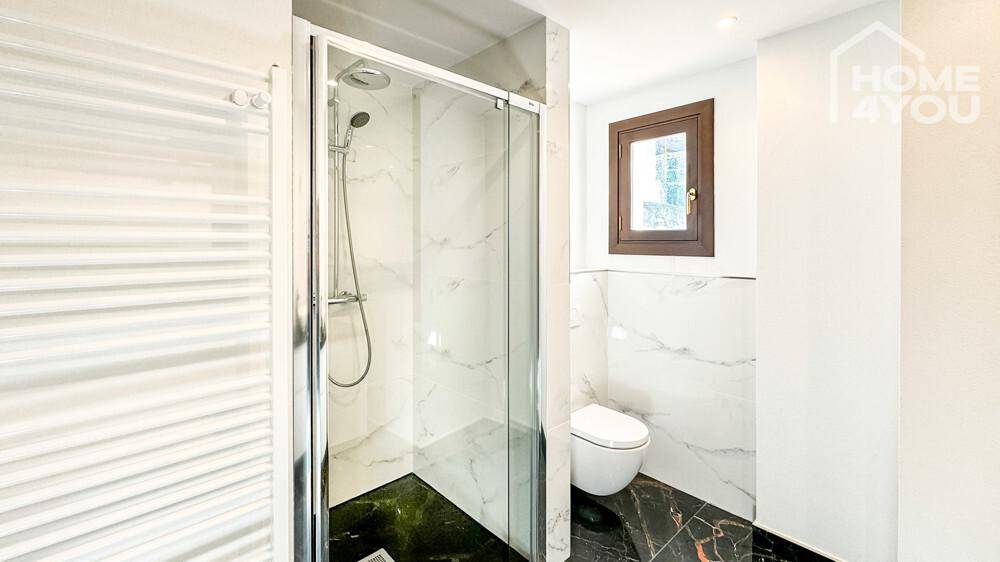 Modernes Badezimmer mit Duschkabine, wandhängendem WC und beheiztem Handtuchhalter.
