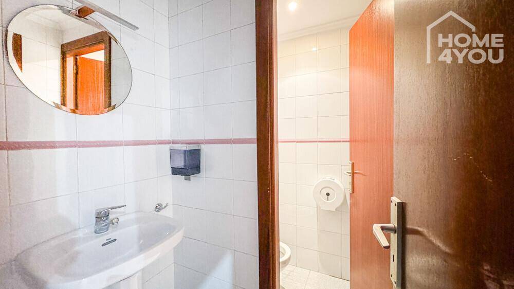 Kleines Badezimmer mit Waschbecken, Spiegel und weißen Fliesen, ideal als Gästetoilette.