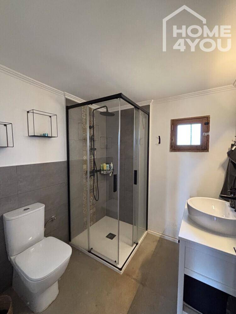 Modernes Badezimmer mit Eckdusche, WC, Einzelwaschbecken und Fenster.