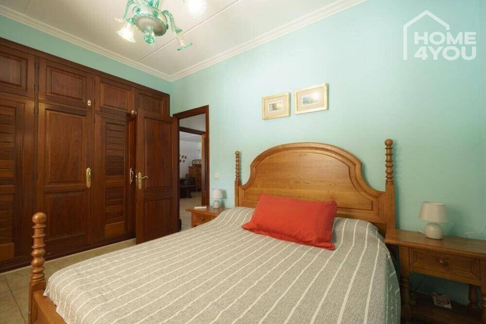 Gemütliches Schlafzimmer mit Holzbett, Einbauschränken und hellblauen Wänden.