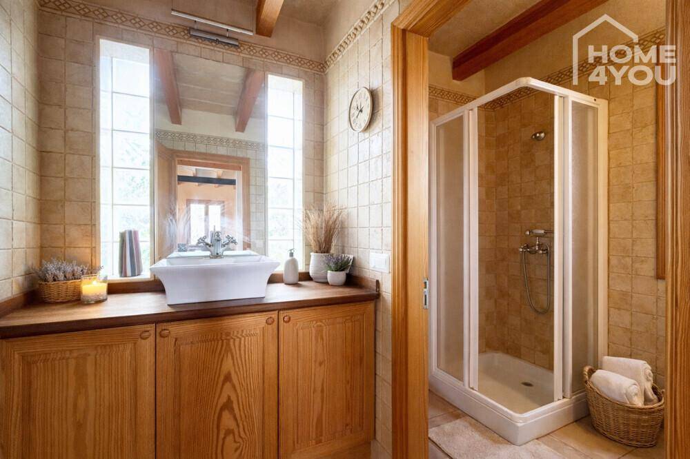 Rustikales Badezimmer mit Holzwaschtisch, beigen Fliesen und Duschkabine.