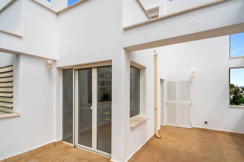 Kleine Terrasse mit Fliesenboden und Zugang zu Innenräumen durch Glasschiebetüren.