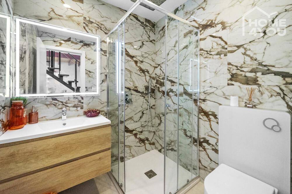Elegantes Badezimmer mit luxuriösen Marmorfliesen, begehbarer Dusche und modernem Waschtisch.