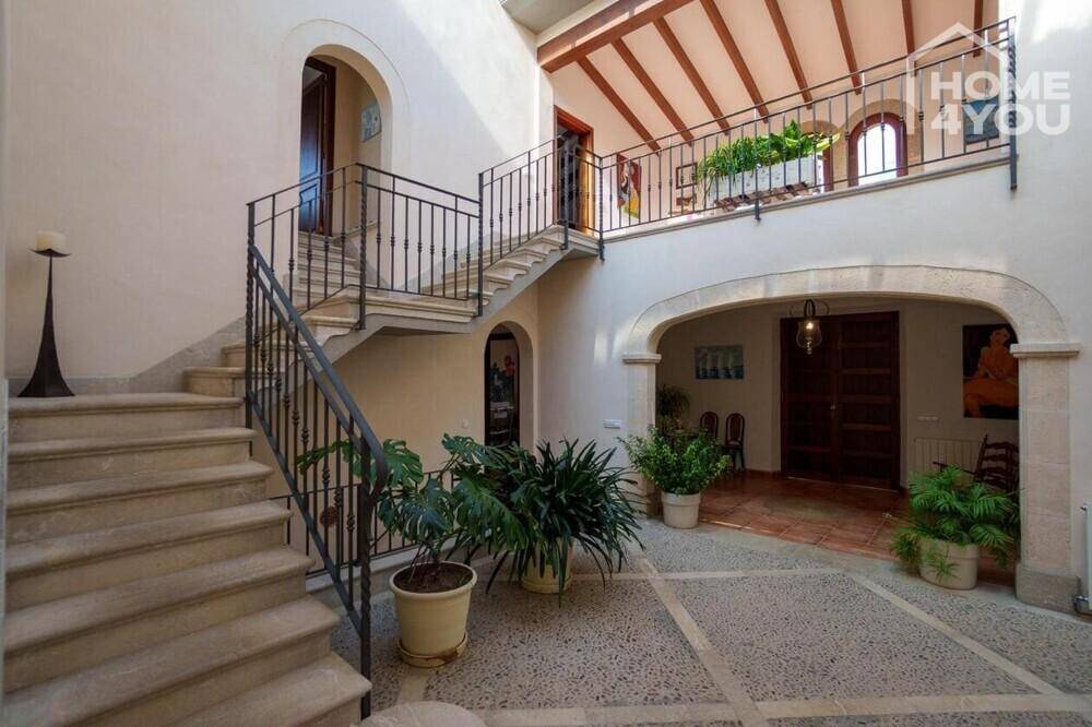 Heller Innenhof mit Steintreppe, schmiedeeisernem Geländer und mediterranen Pflanzen.