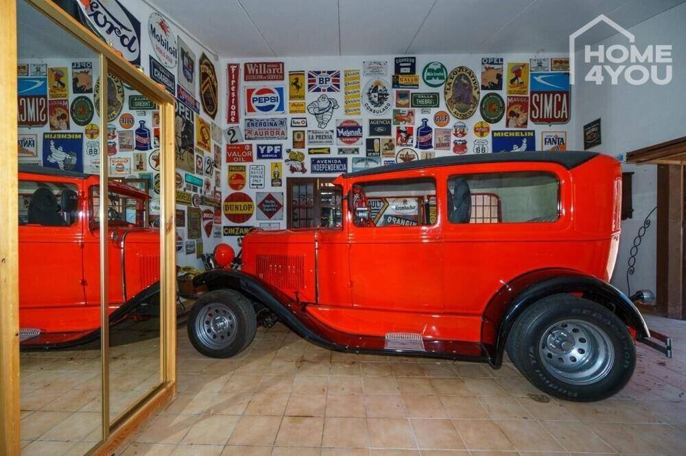 Einzigartige Garage mit Oldtimer und Wänden voller Vintage-Werbeschilder.