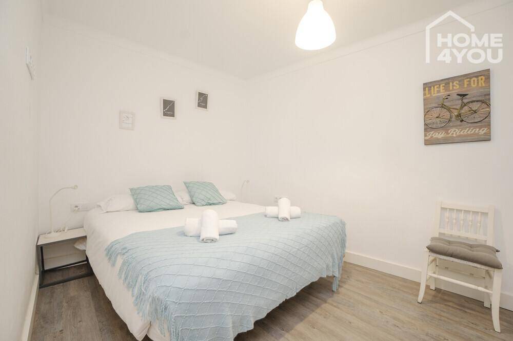 Gemütliches Schlafzimmer mit Doppelbett, hellblauer Bettwäsche und modernem Laminatboden.