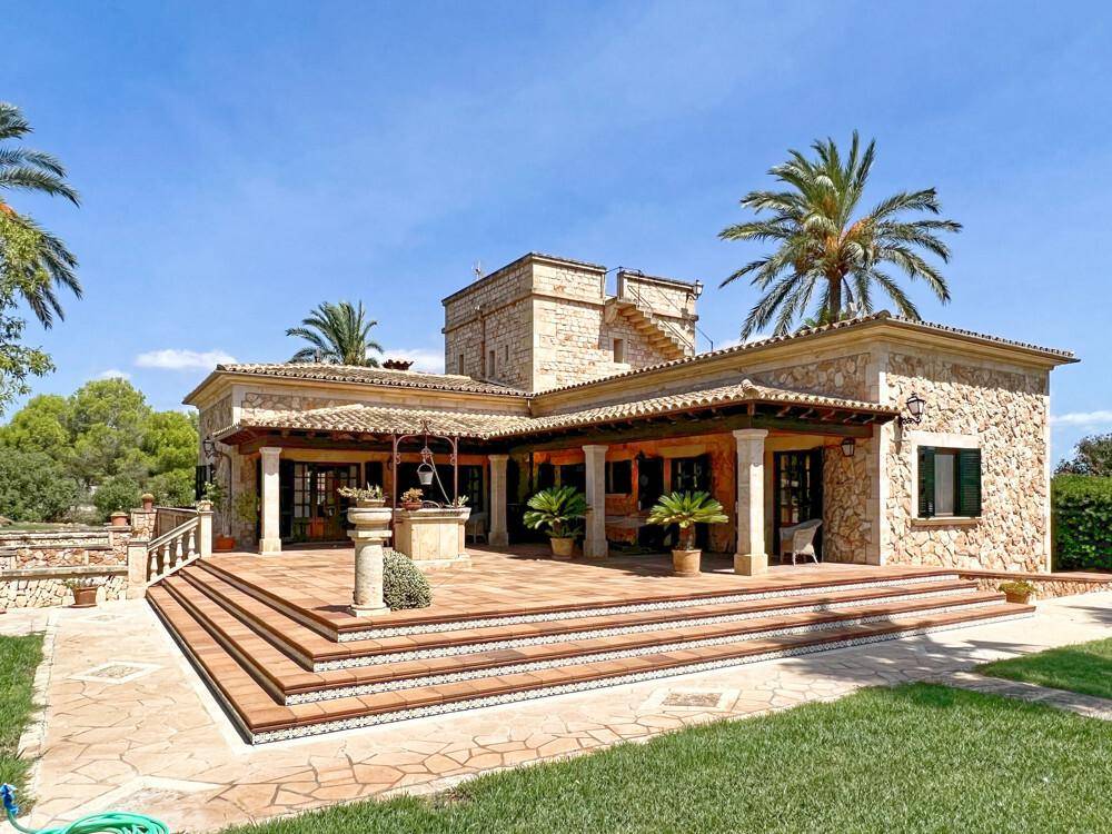 Großzügige, geflieste Terrasse mit Stufen und überdachtem Bereich, ideal für Mahlzeiten im Freien.