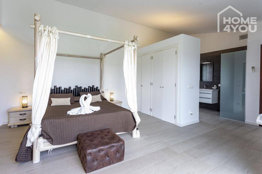 Geräumiges Schlafzimmer mit Himmelbett, Einbauschränken und angrenzendem Badezimmer.