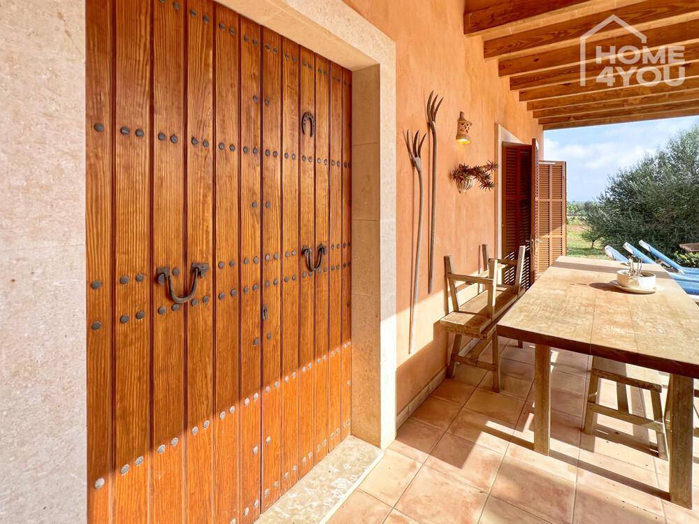 Überdachte Terrasse mit Holztisch und Stühlen, ideal für Mahlzeiten im Freien.