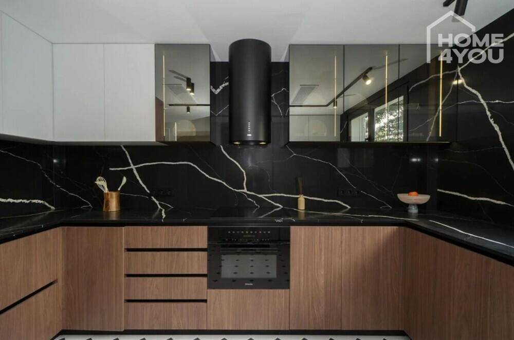 Moderne Küche mit schwarzen Marmorarbeitsplatten, Holzfronten und integrierten Geräten.