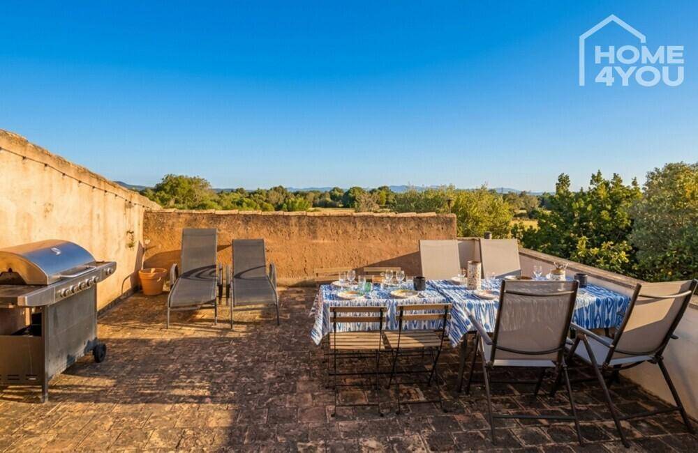 Große Dachterrasse mit Grillbereich, Esstisch und Liegestühlen unter freiem Himmel.
