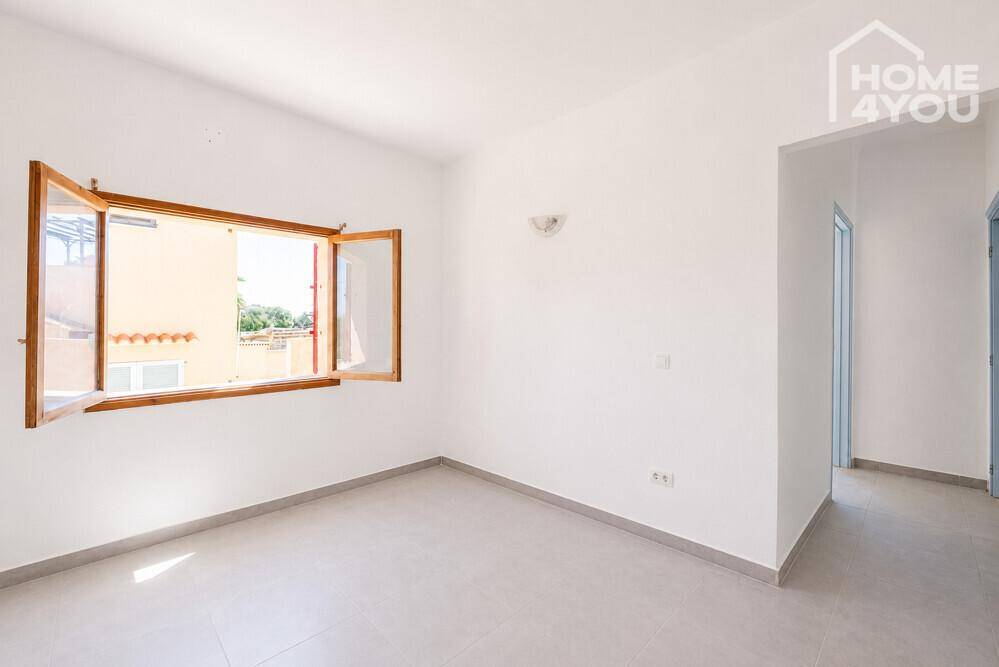 Helles Schlafzimmer mit Fliesenboden, weißen Wänden und einem Fenster, das den Raum erhellt.