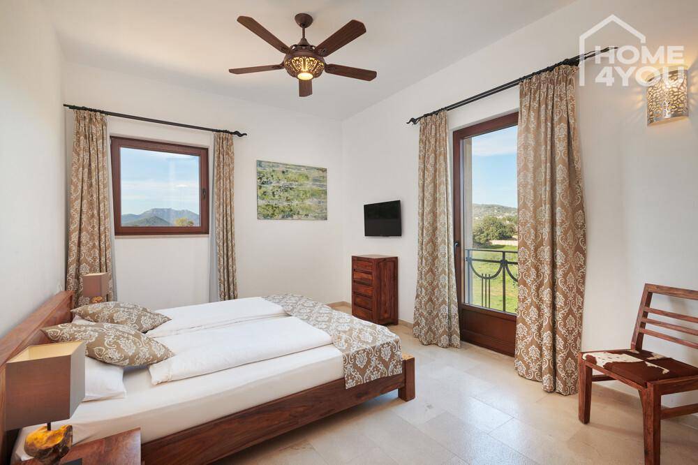 Komfortables Schlafzimmer mit Deckenventilator, Fliesenboden und französischem Balkon.