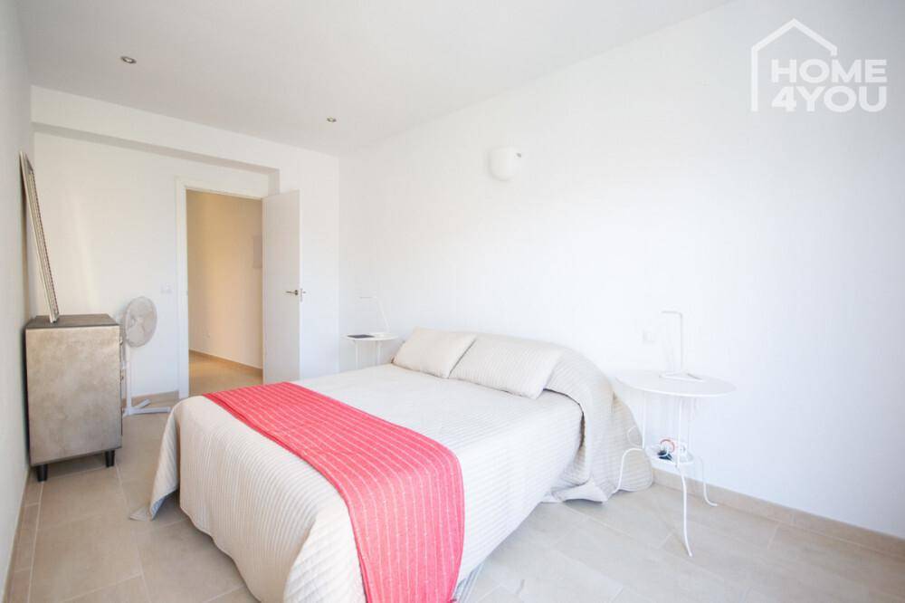 Schlichtes Schlafzimmer mit Doppelbett, Nachttischen und weiß gestrichenen Wänden.