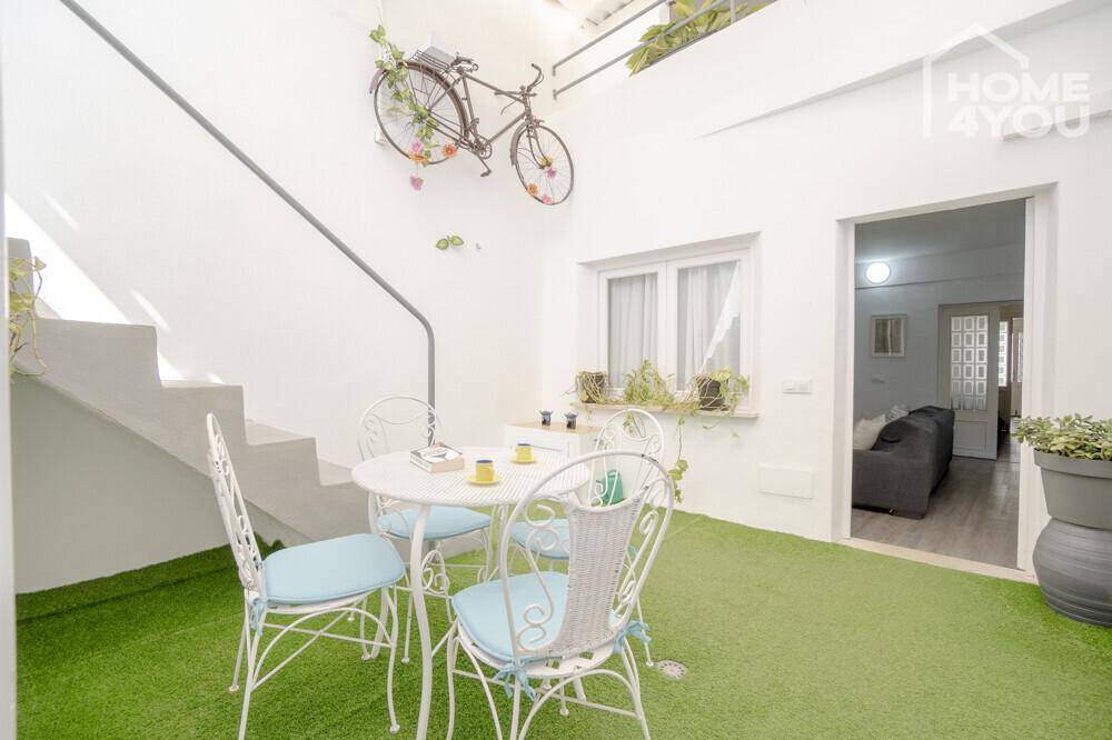 Kleiner Innenhof mit Kunstrasen, Sitzgelegenheiten und einer Treppe, charmant dekoriert.