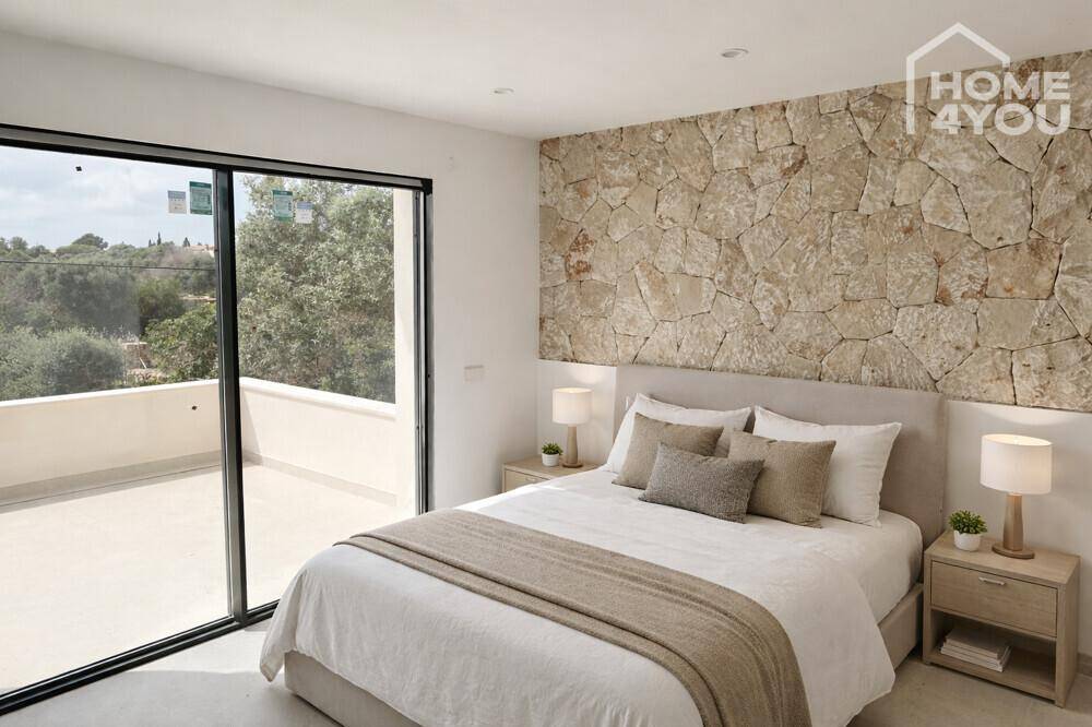 Helles Schlafzimmer mit Steinwandakzent, Doppelbett und Zugang zur Terrasse.