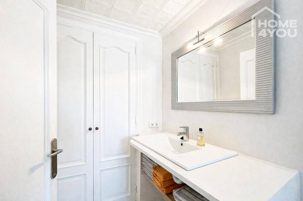 Kleines Badezimmer mit Einzelwaschbecken, Spiegelschrank und weißen Doppeltüren.