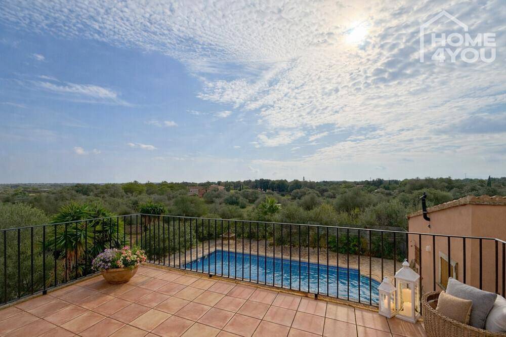 Sonniger Balkon mit Terrakottafliesen und weitem Panoramablick über die grüne Landschaft.
