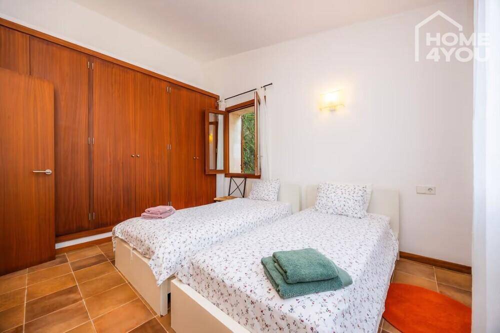 Komfortables Schlafzimmer mit zwei Einzelbetten, Einbauschränken und Terrakottaboden.