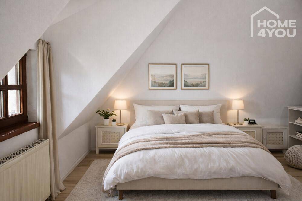 Gemütliches Schlafzimmer im Dachgeschoss mit schrägen Wänden, hellem Bett und Fenster.