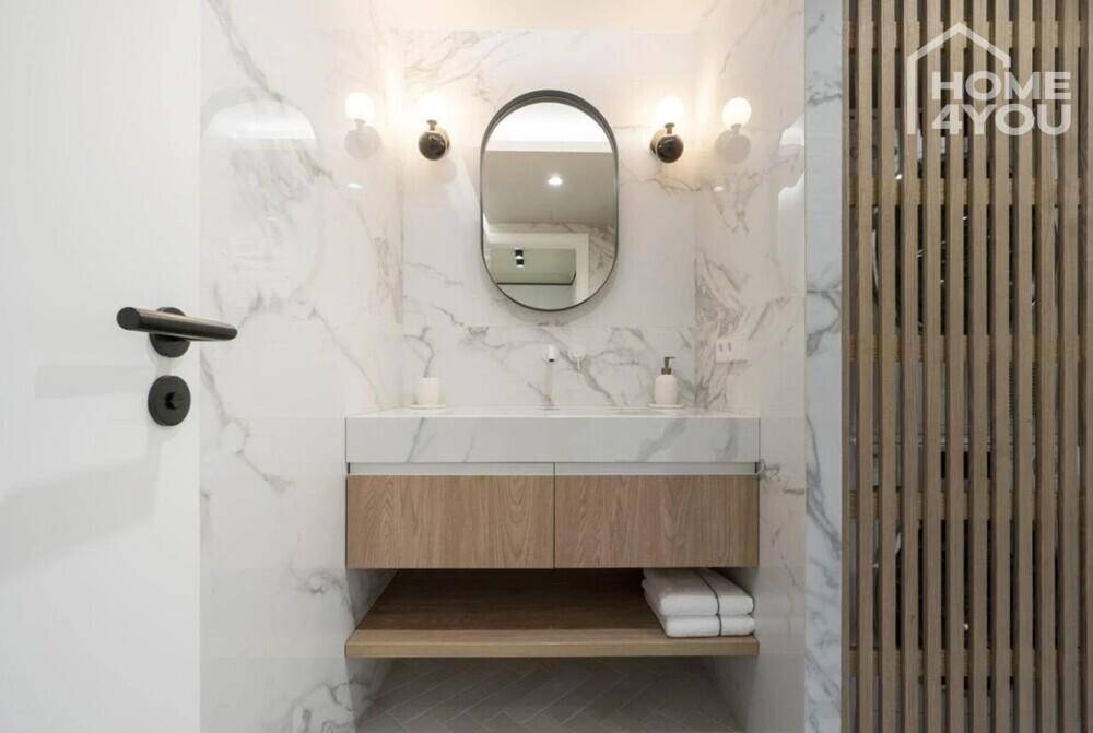 Modernes Badezimmer mit Marmorfliesen, Holzwaschtisch und ovalem Spiegel.